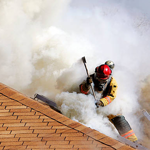 A Fire Fighter uses an axe to vent the roof of a house that is on fire.  Non training event.